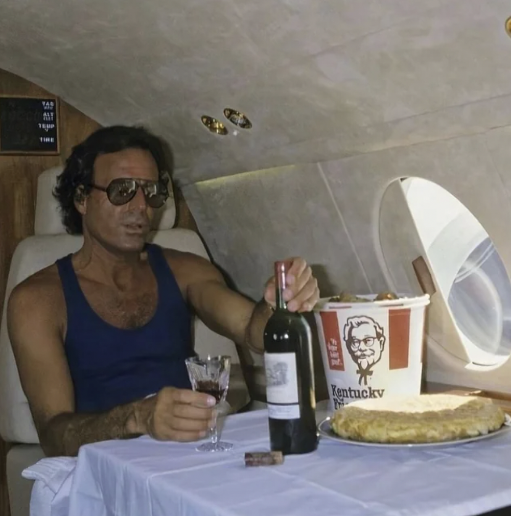 Julio Iglesias on his private jet with a bottle of wine and a bucket of KFC.