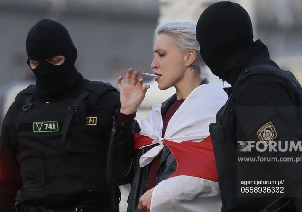 Woman smoking a cigarette while being arrested.