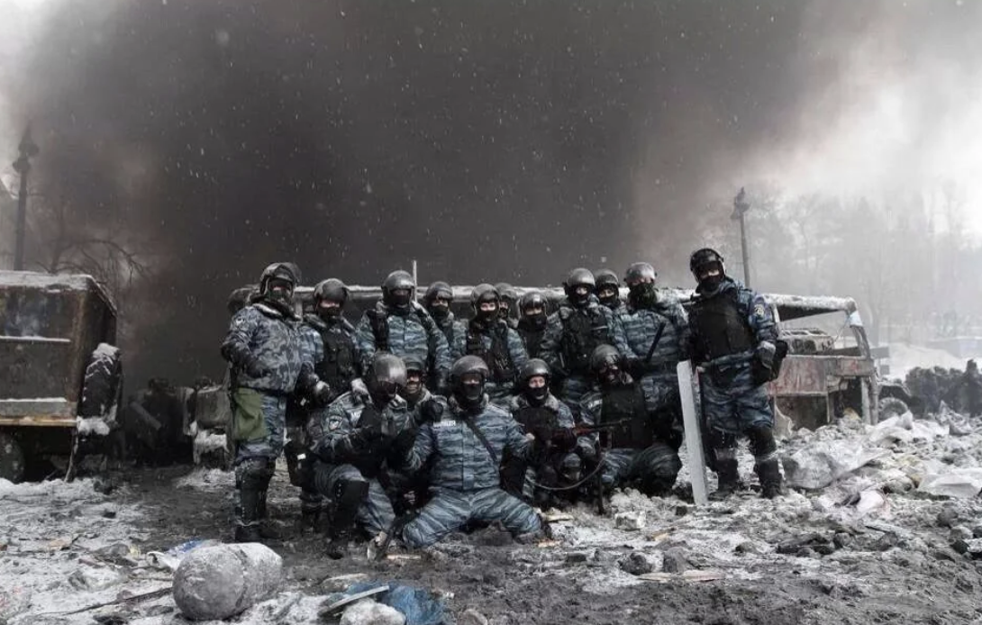 Kiev riot police pose for group photo amid destroyed street.