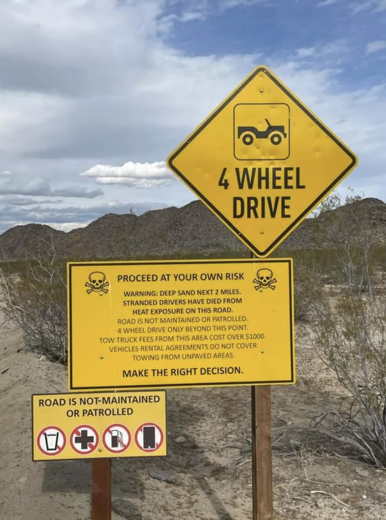 traffic sign - 4 Wheel Drive Proceed At Your Own Risk Warning Deep Sand Next 2 Miles Stranded Drivers Have Died From Heat Exposure On This Road. Road Is Not Maintained Or Patrolled 4WHEEL Drive Only Beyond This Point Tow Truce Fees From This Area Cost Ove