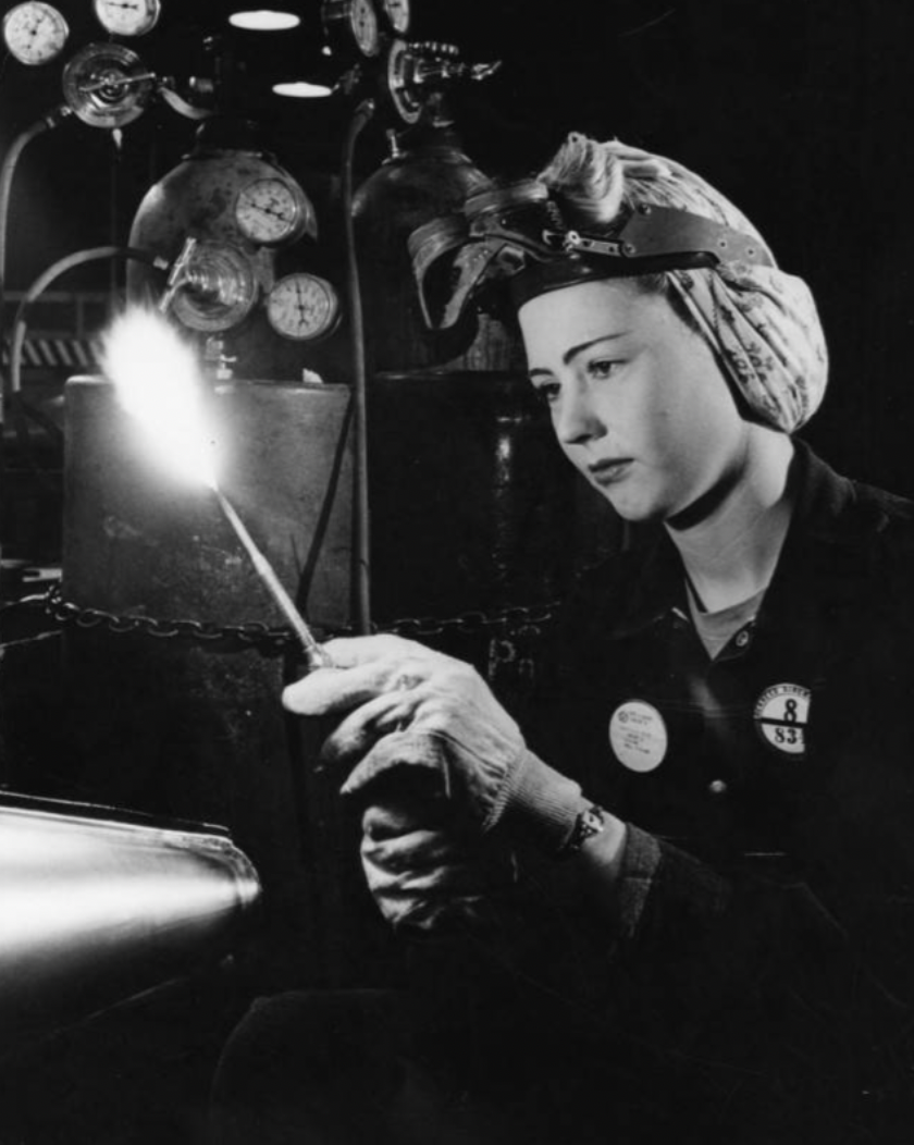 Woman holding a welding torch at an aviation factory during WW2 in Los Angeles.