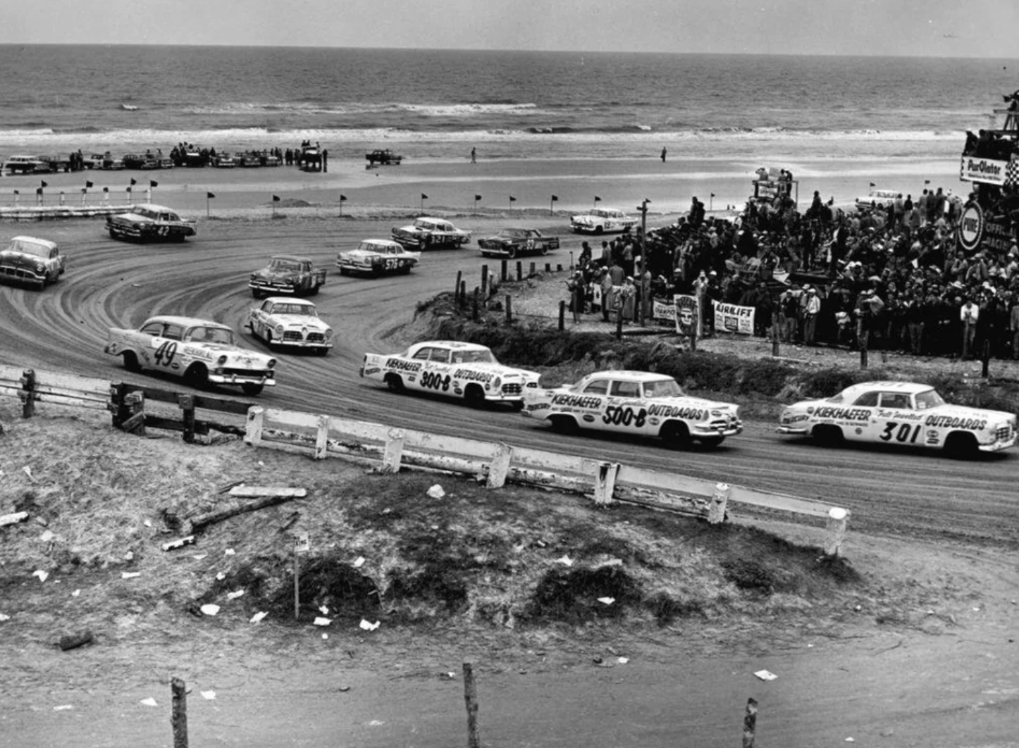 Carl Keikhafer cars, lead by Buck Bakerin his #301 1955 Chrysler, race through the south turn during the Beach and Road Course race in Daytona Beach Florida, 1956.