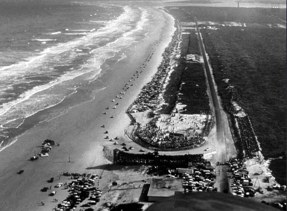 An aerial view of the North Turn and grandstand as cars race on the Daytona Beach Road Course in 1950.