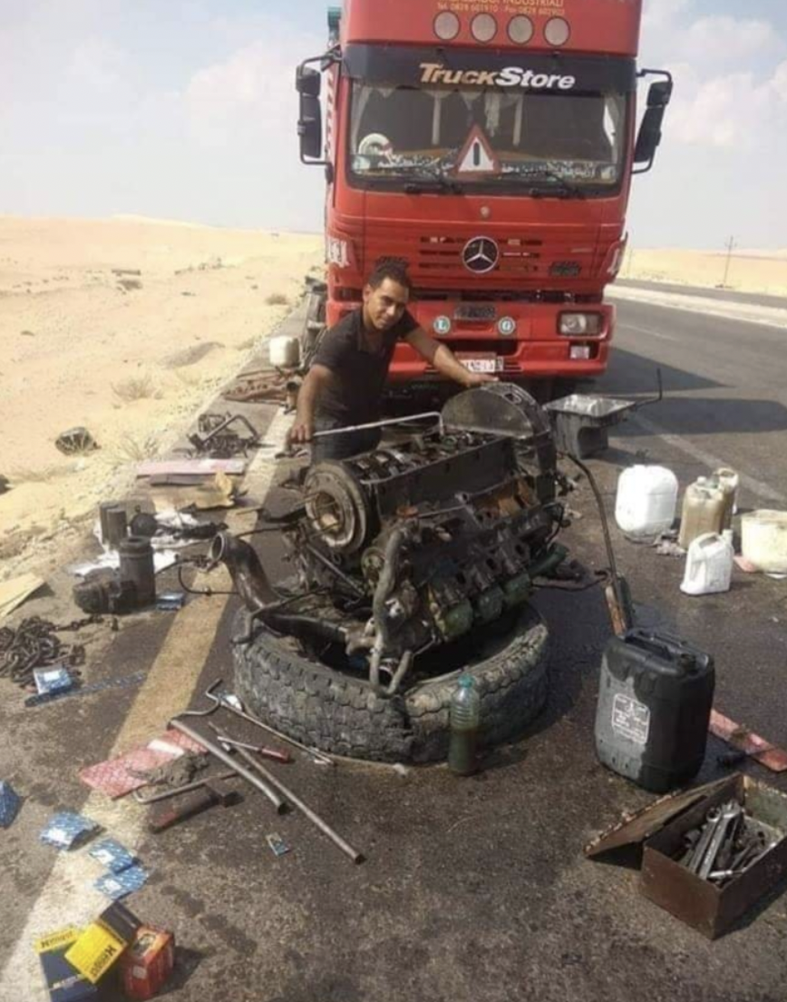 guy rebuilding truck engine in desert - TruckStore