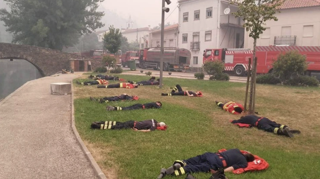 “Exhausted firefighters resting after fighting multiple fires that are still fustigating Central Portugal.” 2017.