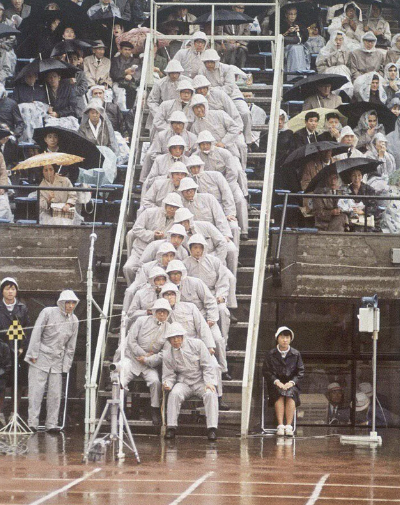 The 1964 Olympic Games: People in white were observers at the running events. At that time, video recording was not yet used, and about 20 people would watch the finish line to track the runners.