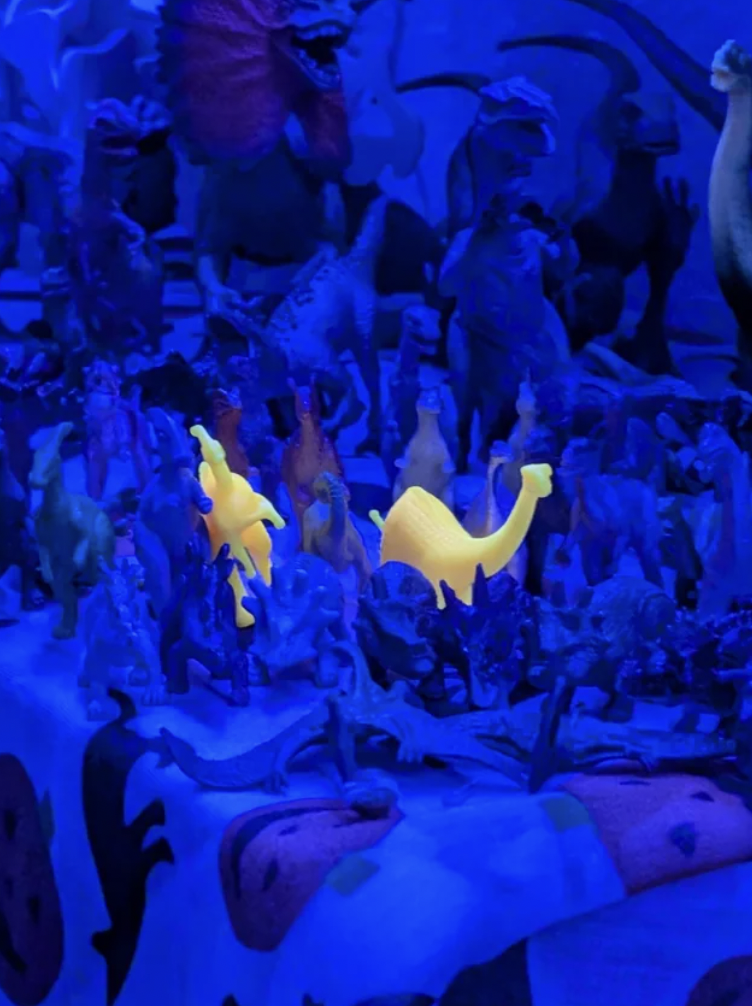 "Some of my plastic dinosaurs glowing under a blue light."