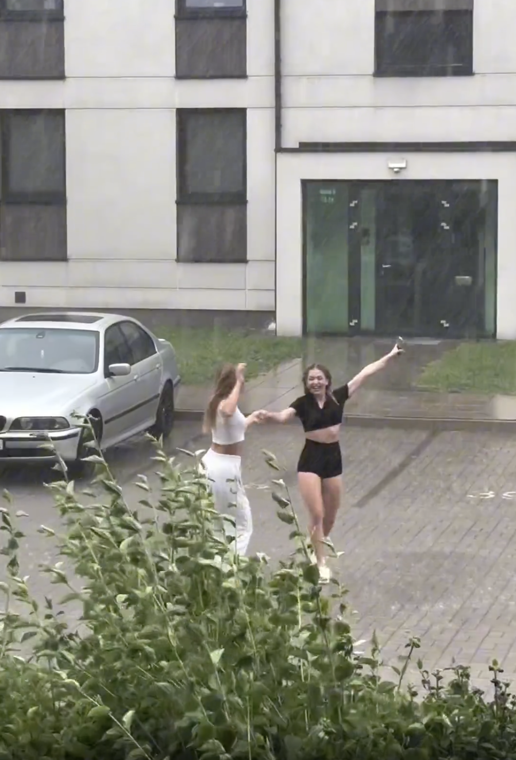 Friends dancing together in the pouring rain. 