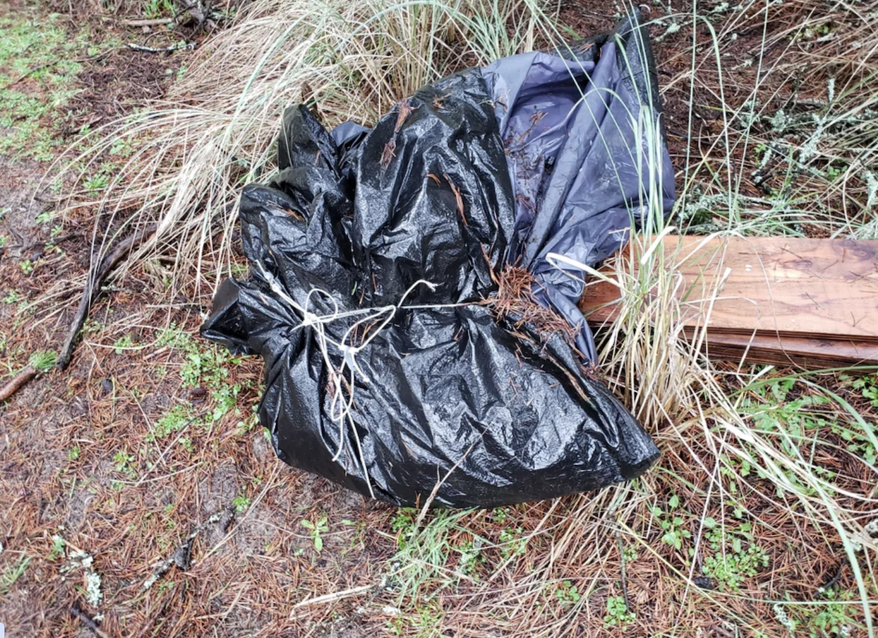 “Found this while doing volunteer trash cleanup. Something wrapped up in a tarp weighed down by heavy boards at the opening. I tugged on it and didn't like how it made me feel, so I reported it to the police. Do you think this is weird? Am I freaking out over nothing?”