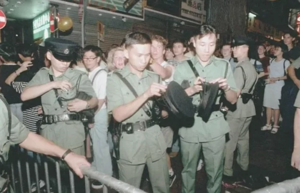 Hong Kong Police officers change cap badges at the stroke of midnight following the handover of sovereignty to China, 1997.