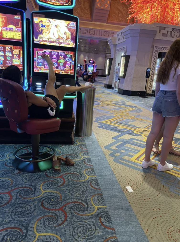 Woman uses her feet to play the slot machine in a casino.