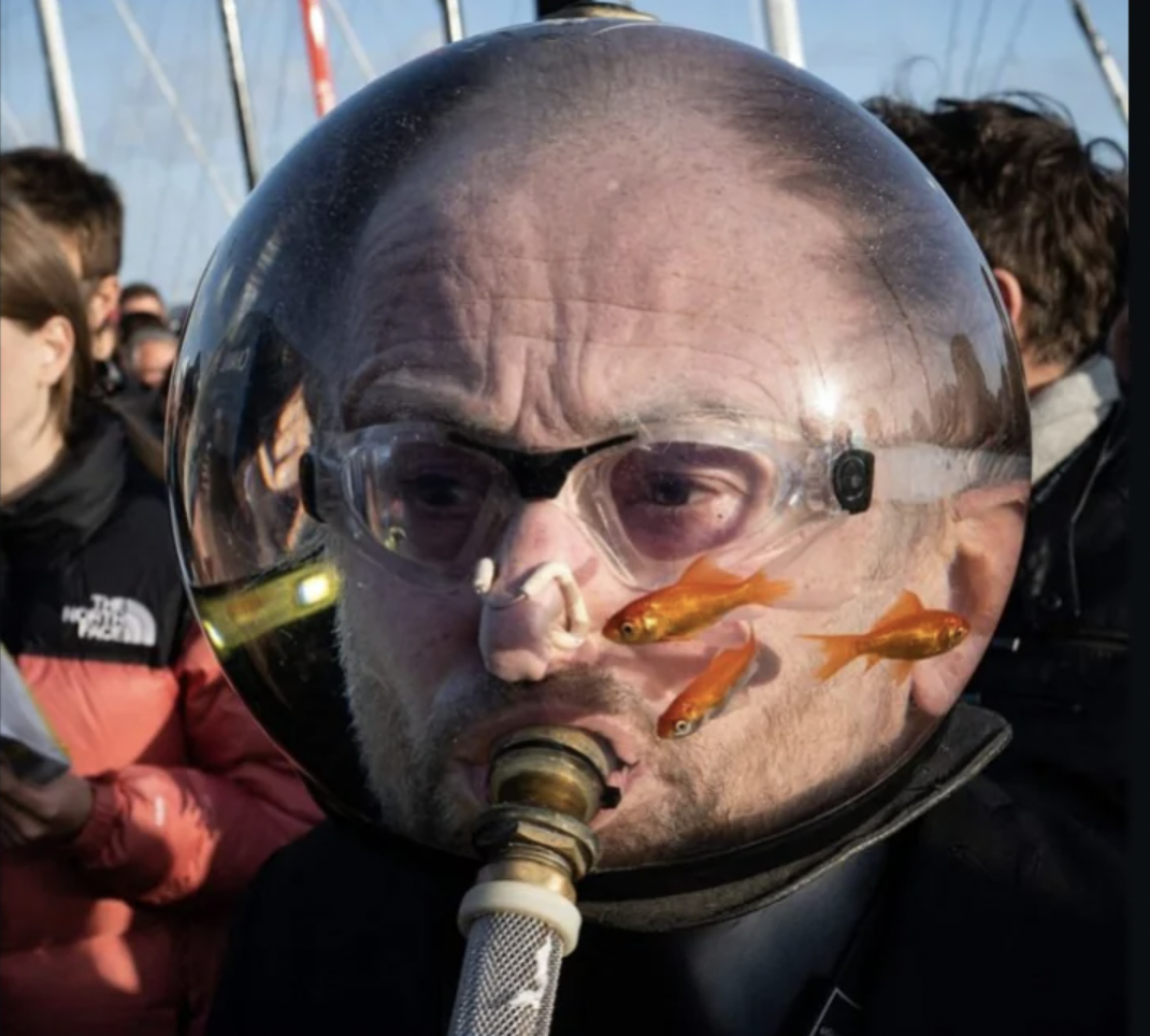 The Aquamen are part of the French theater group "Machtiern." They are known for wandering around with fish bowls on their heads containing live fish.