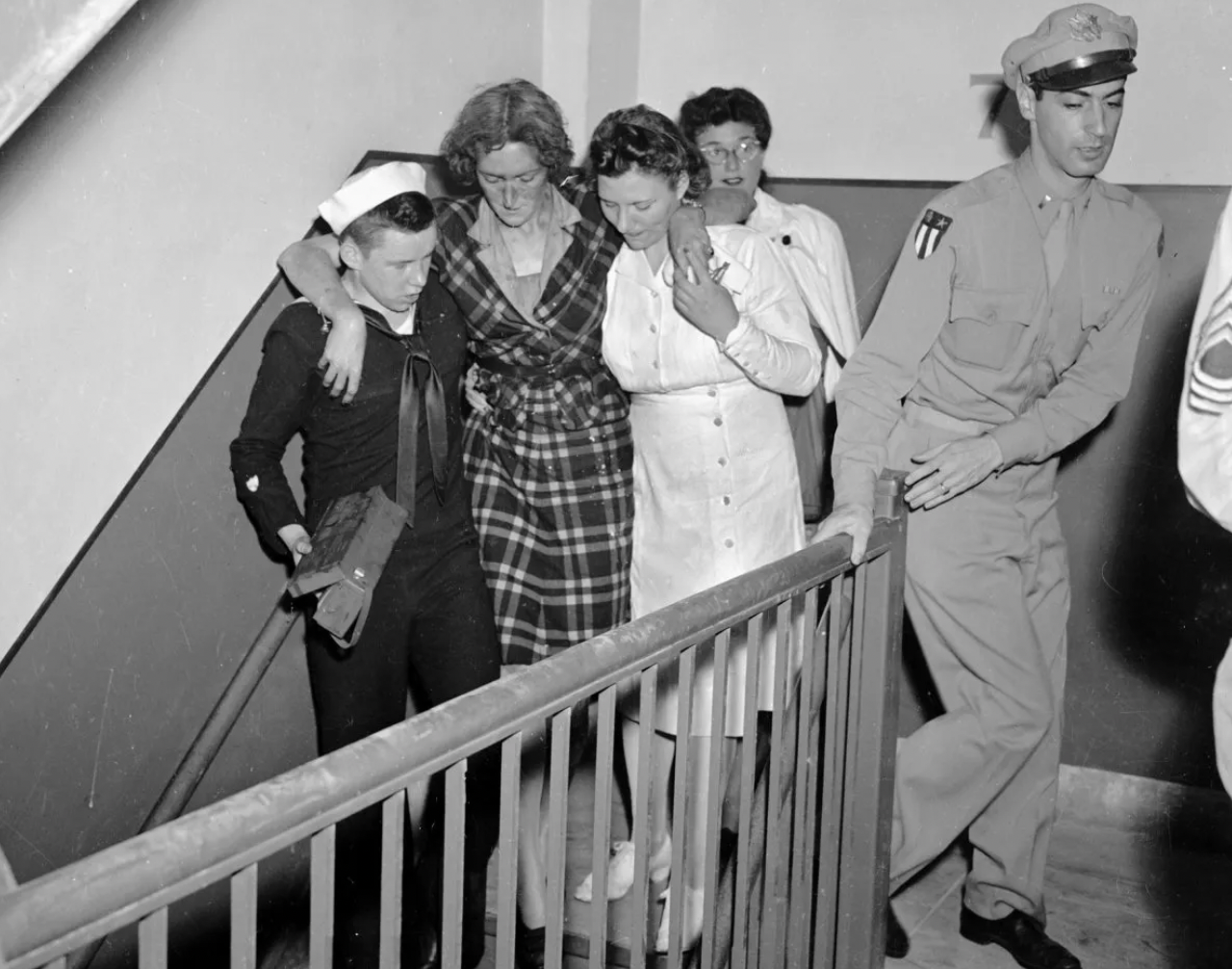 Don Malony (L), a Coast Guardsman, carries a first aid kit as he helps an injured woman down the stairs.