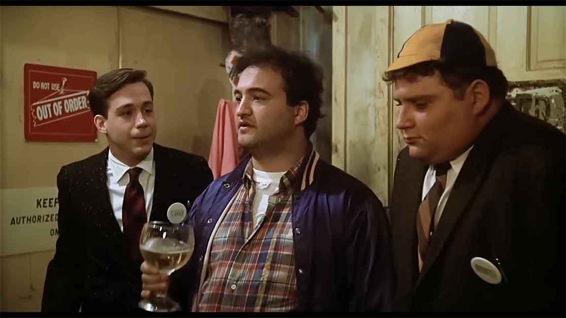 Bluto confidently walks into a rowdy party with his beer, much to the amazement of Pinto. 