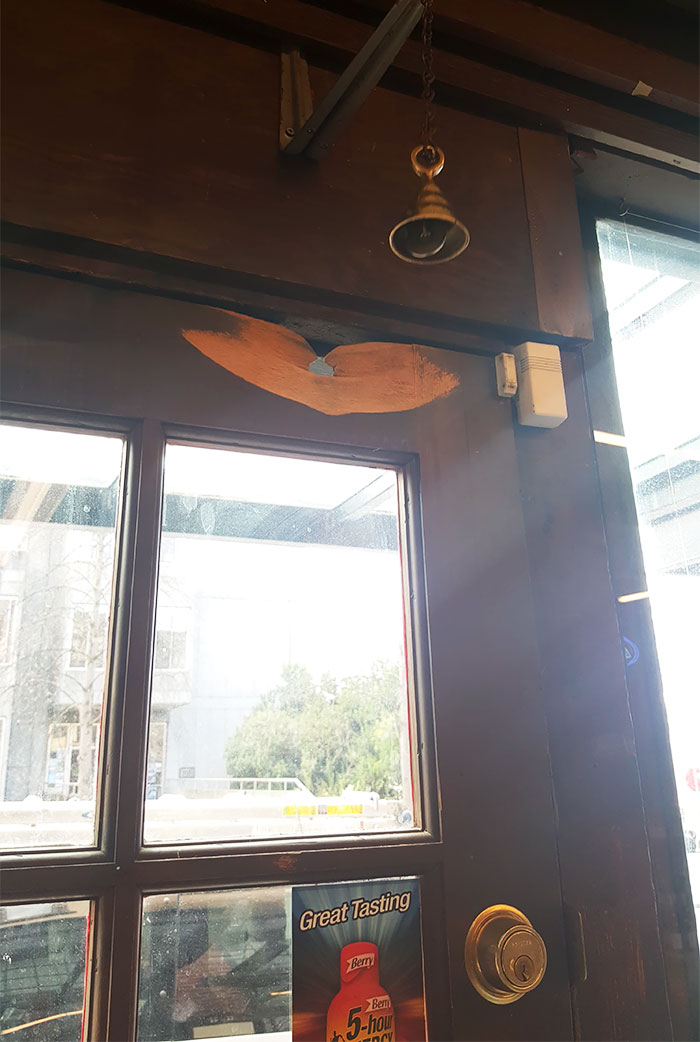 This bell that alerts the shop owner when someone comes into the shop has worn a hole completely through the top of the door that it hits against.