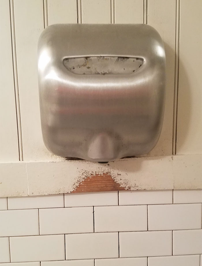 Water from wet hands combined with the air from this hand-dryer has 'washed away' some of the paint on this bathroom wall.