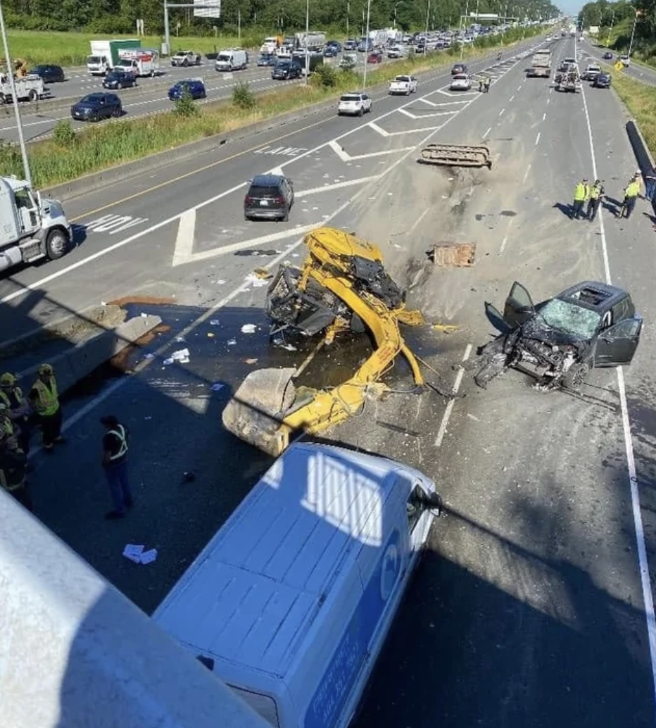 Vancouver BC, a dump truck towing an over height excavator hits a bridge, and vehicles following. July 12, 2022.