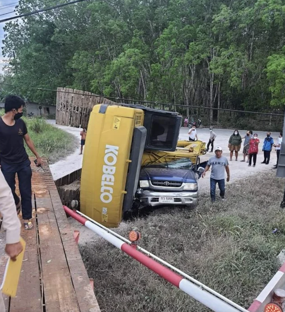 Truck loaded with excavator crossed railroad tracks at a bad time. Thailand, 2022. 