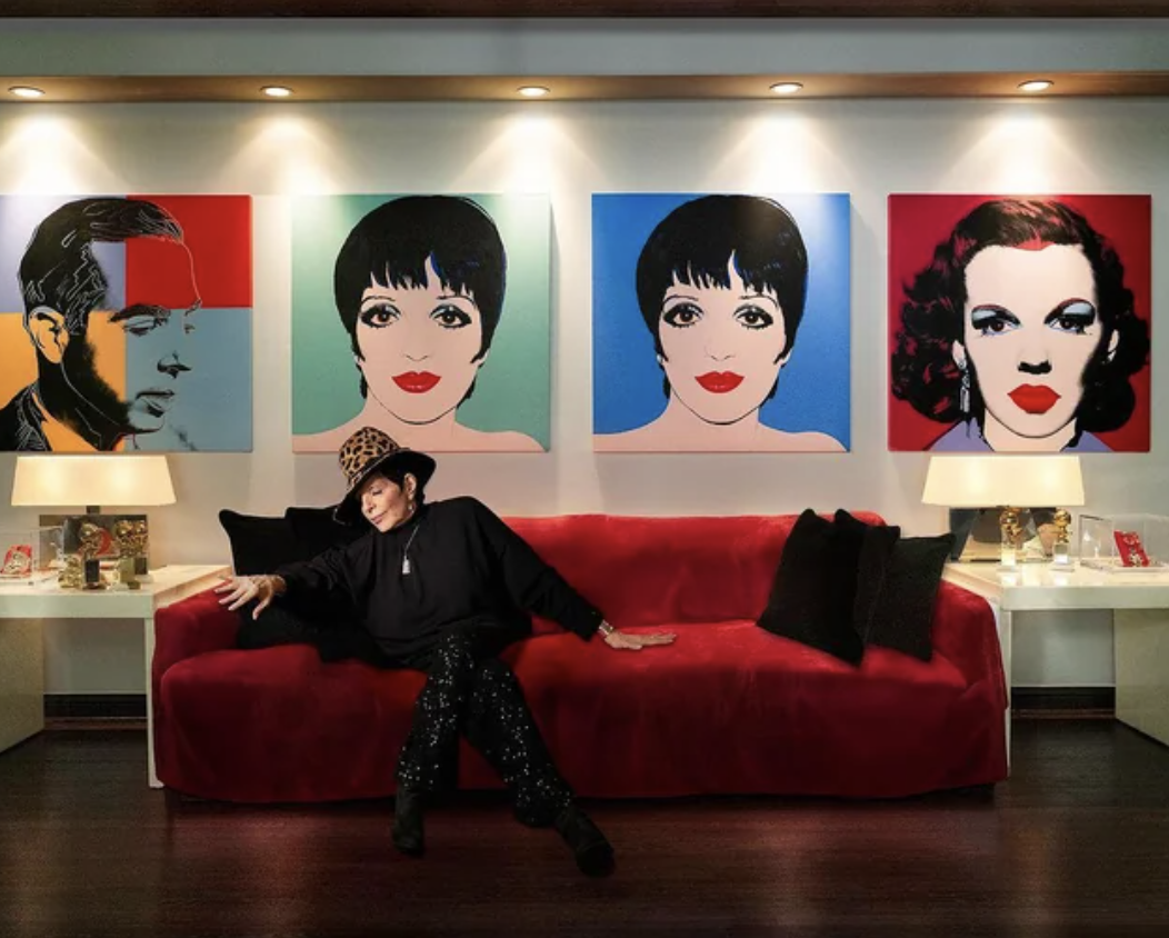 Liza Minnelli sitting in front of Andy Warhol's paintings of her and her parents.