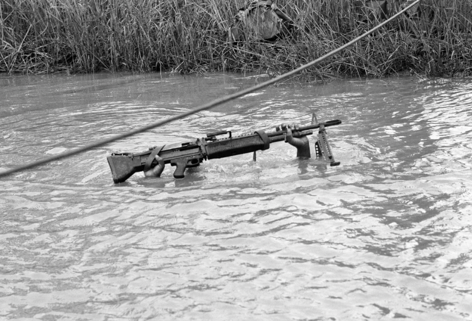 A 6ft 5in machine gunner with the US 9th Infantry Division is submerged except for his rifle as he crosses a muddy stream in the Mekong delta south of Saigon on September 10th, 1968. Photograph: Henri Huet.