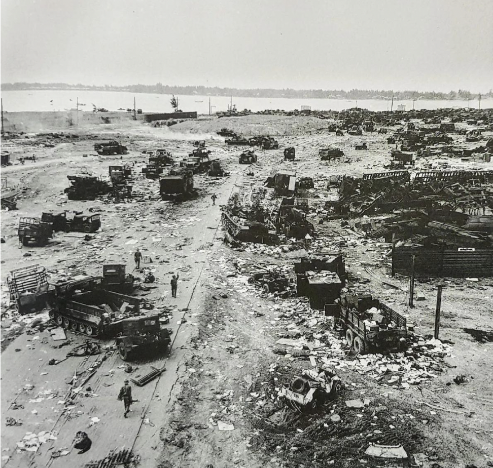 Four North Vietnamese soldiers walking among numerous ARVN military vehicles and equipment abandoned or destroyed on the road of Huế, the Vietnam War, 1975.