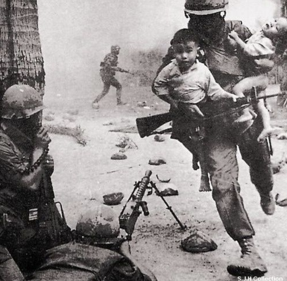 A U.S. Marine rescues two Vietnamese children during a gun battle at the city of Hue, during the Tet Offensive of the Vietnam War, 1968.