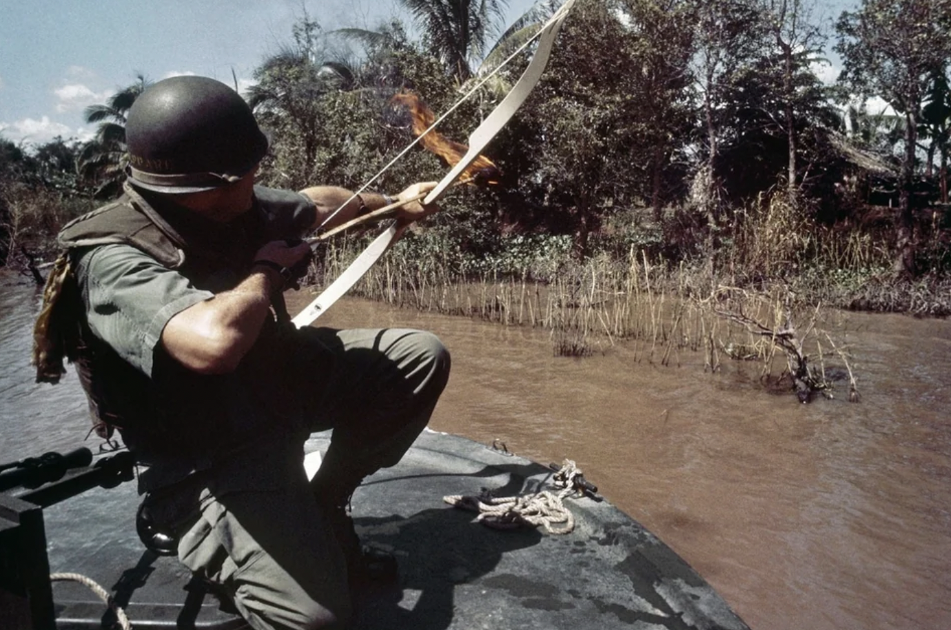 Lieutenant Commander Donald D. Sheppard, of Coronado, California, aims a flaming arrow at a bamboo hut concealing a fortified Viet Cong bunker on the banks of the Bassac River, South Vietnam, on December 8, 1967.