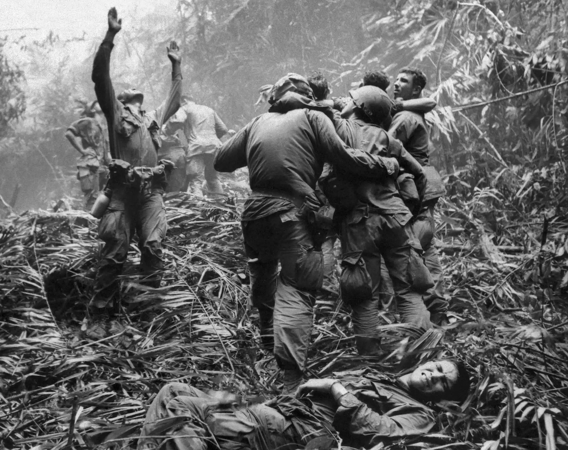 As fellow troopers aid wounded comrades, a paratrooper of A Company, 101st Airborne Division, guides a medevac helicopter through the jungle.