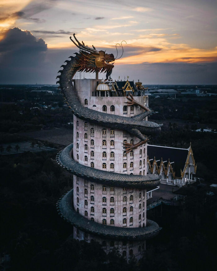 The right weather and perfect time of day for this photo make it appear as if a fire-breathing dragon is climbing up a building. The building is known as Wat Samphran is the mystical, and awe inspiring Dragon Temple located just outside of Bangkok city.