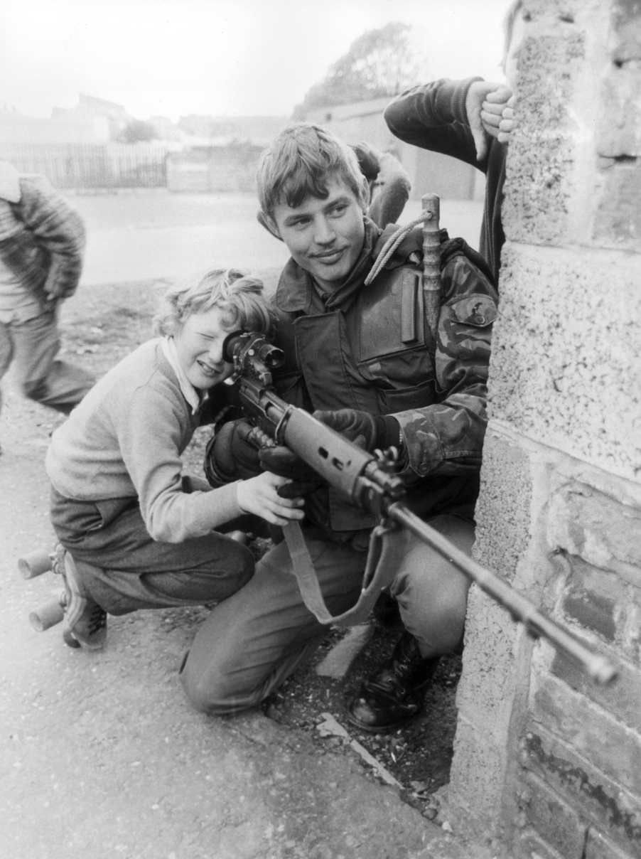 A British soldier lets a young boy look through the sights of his rifle in Belfast, 1981.