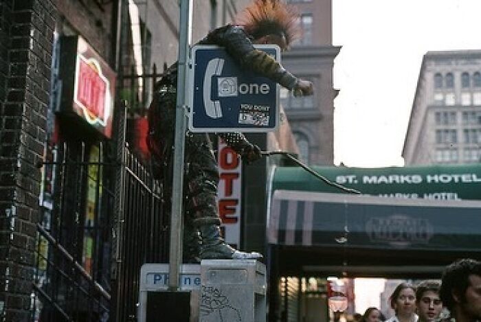 A punk rocker stands atop a Payphone on the sidewalk near St. Marks Place in 1993 