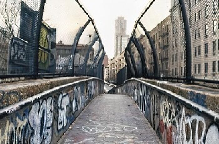 A sidewalk path over the freeway decorated with graffiti in the Upper East Side.