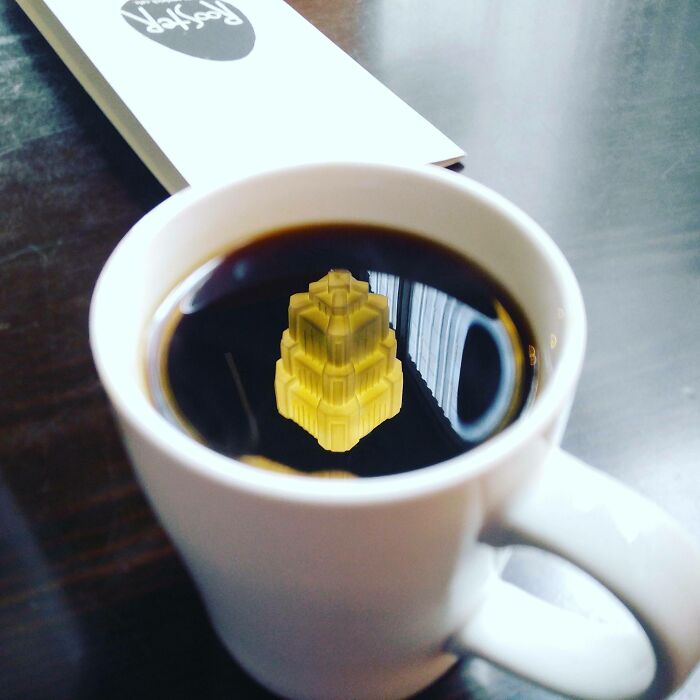 The chandelier's reflection make it seem like a tiny glowing castle is in this coffee cup.