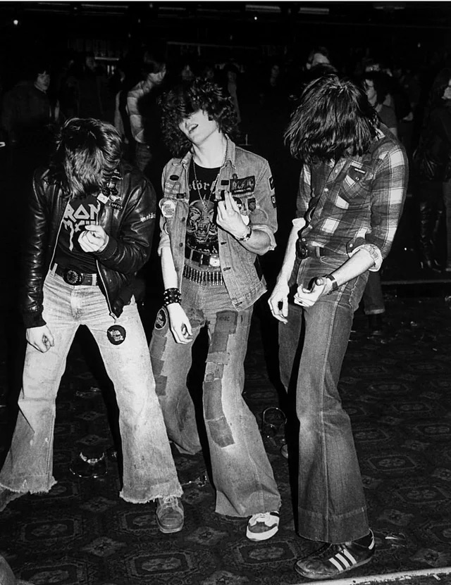 Metalheads playing air guitar at an Iron Maiden concert in 1980.