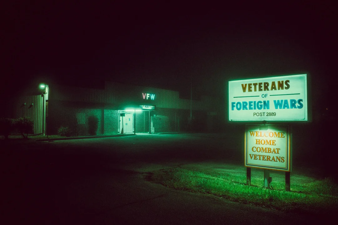 A welcome sign that keeps flickering under hazy greens.