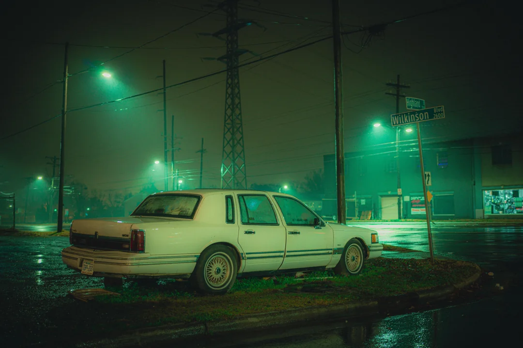 A sedan waiting for years under the lights.