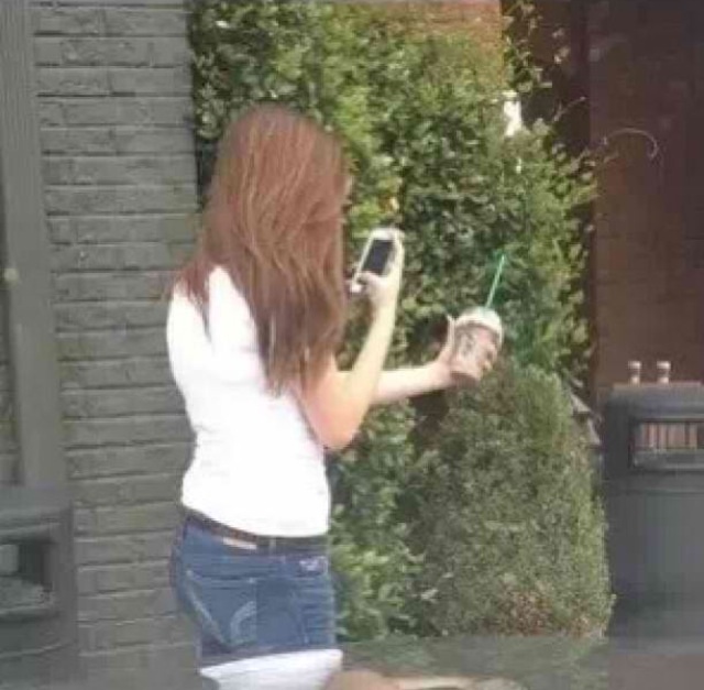 The white girl Instagrammer in her natural environment, taking a picture of her frappuccino.