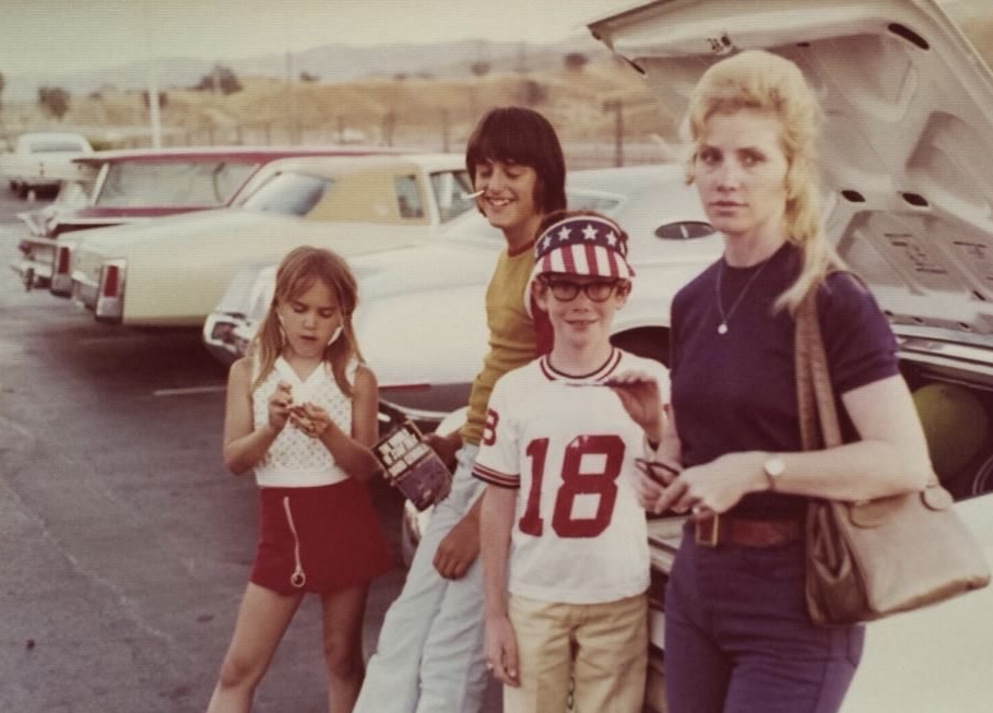 Backseat unbuckled. Windows down. Mom’s perm holding strong.