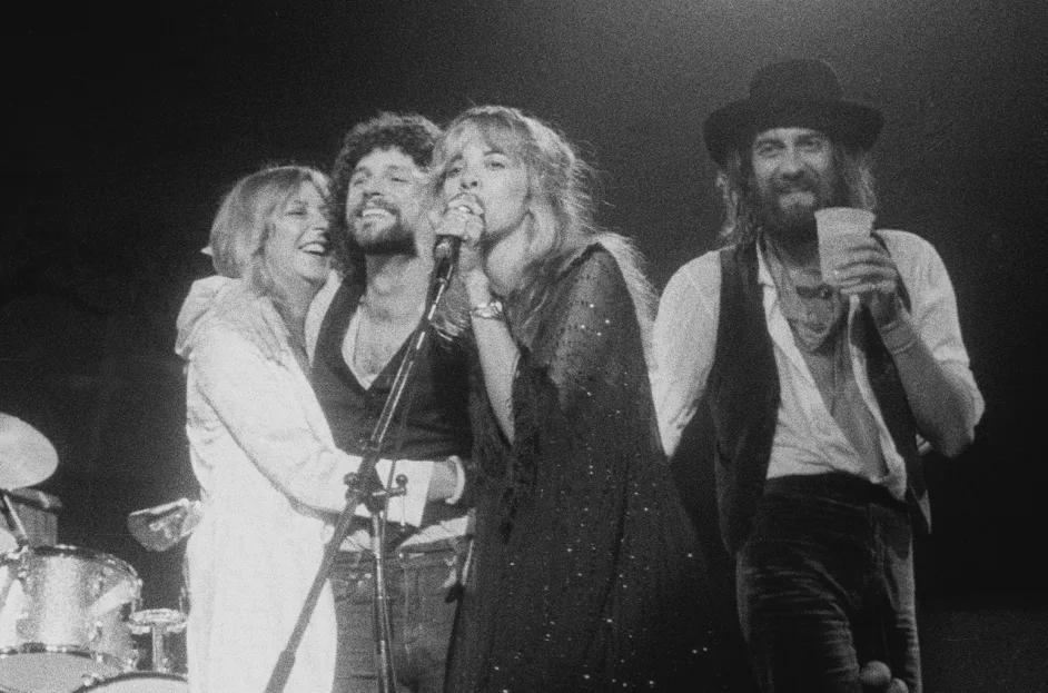 The band gathered around the microphone in a moment of unity in 1977, Stevie front and center, with Christine, Lindsey, and Mick sharing the spotlight.