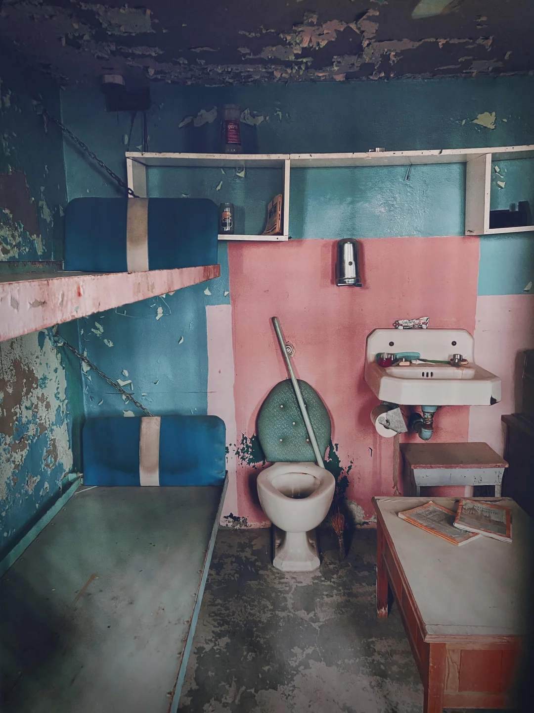 Crumbling walls, a metal bedframe, and a shared toilet. This was someone's home once.
