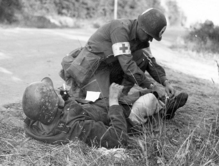 On the roadside, a medic administers first aid.