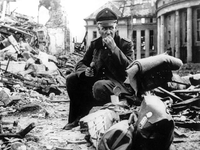 Among devastation, a soldier pauses to have some food.