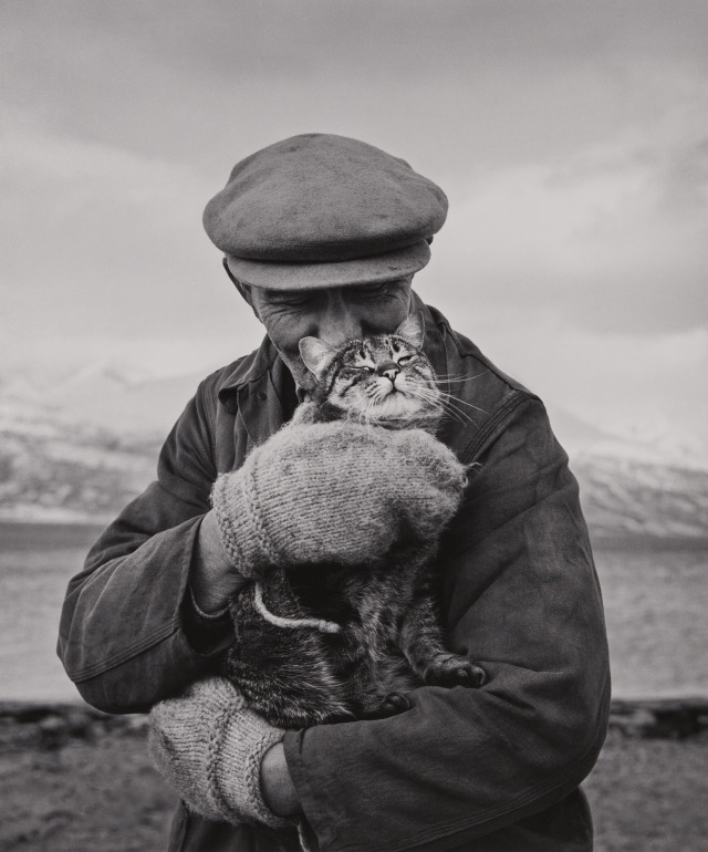 A fisherman cradling his cat against the Arctic chill.