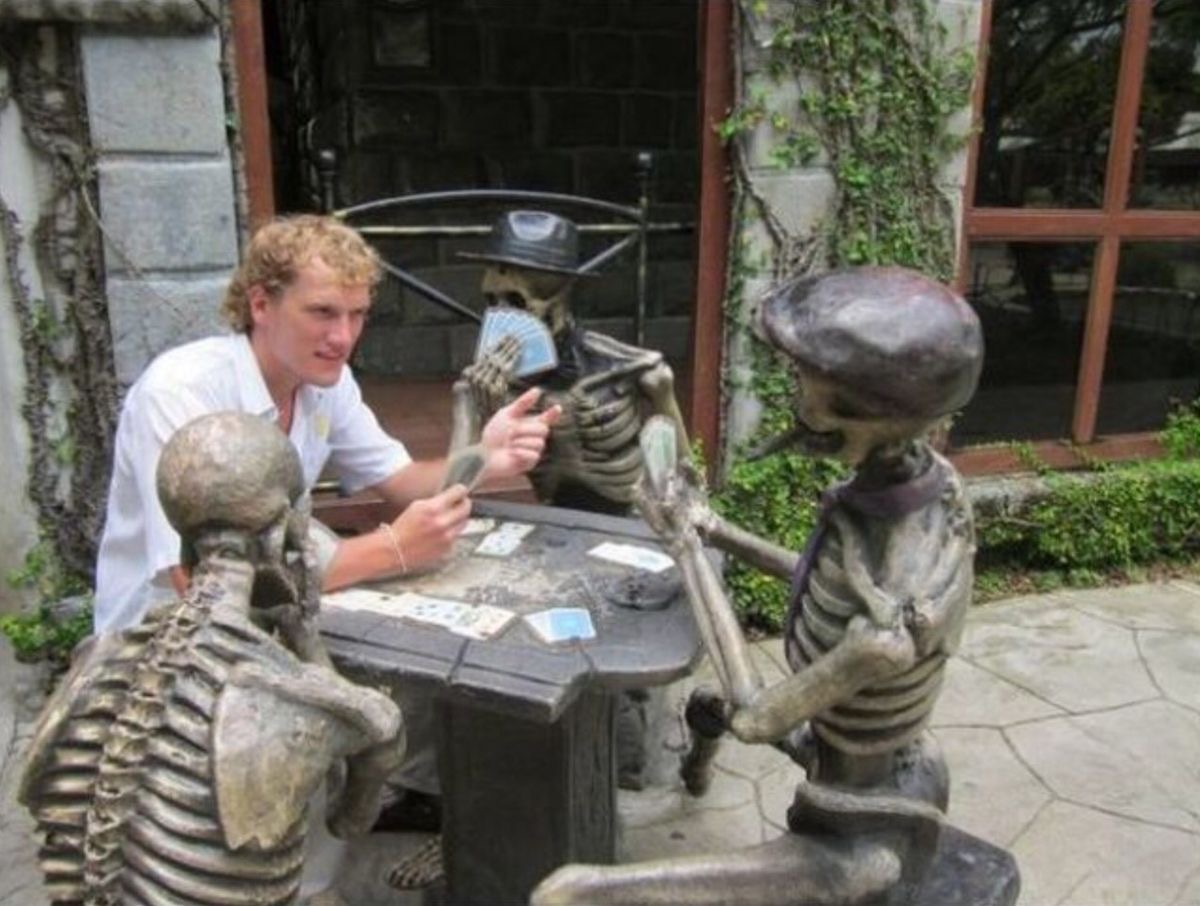 Guy Playing Cards with Skeletons