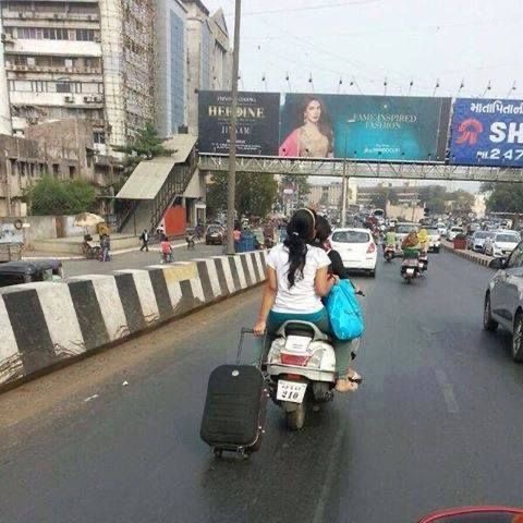 Woman Dragging a Suitcase While On a Motorcycle