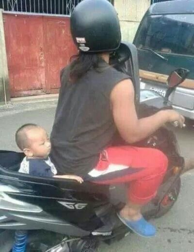 Woman Riding a Motorcycle With a Baby and No Helmet