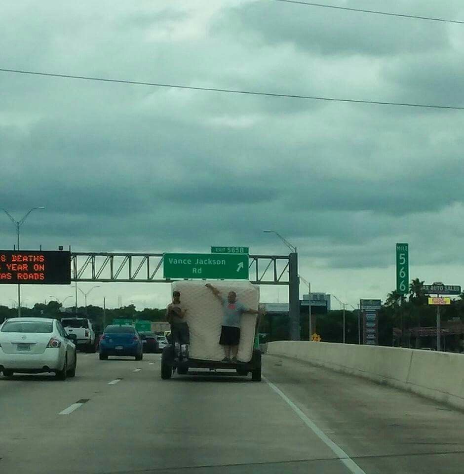 Men Standing in the Back of a Truck Holding a Mattress