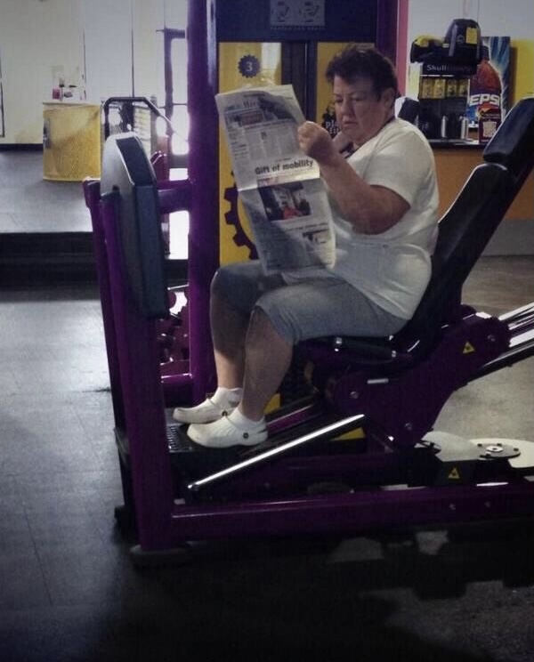 Woman Reading the Newspaper on a Gym Machine
