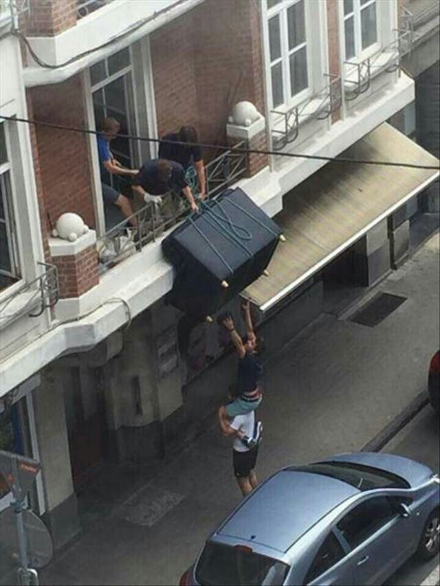 Guys on the First Floor Lowering a Sofa to Other Guys on the Street