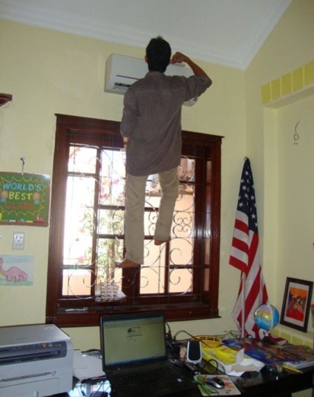 Man Standing on an Office Window Fixing the AC